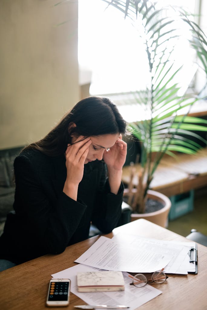 A businesswoman experiencing stress at her desk in a modern office setting.